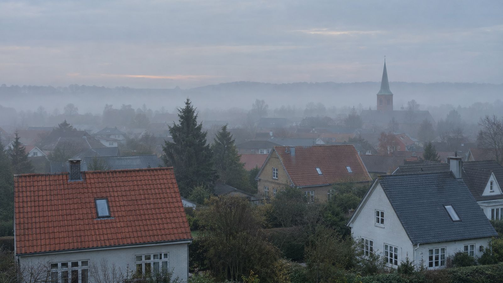 Bredt panorama over danske parcelhustage i lav morgentåge